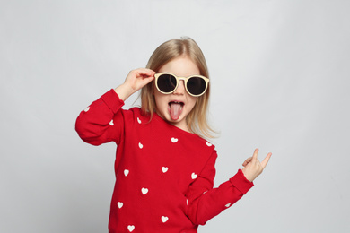 Portrait of cute funny little girl on light grey background