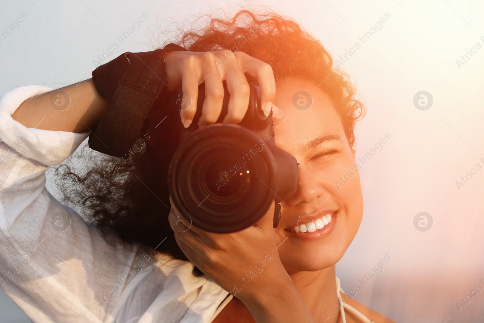 Image of African American photographer taking photo with professional camera outdoors