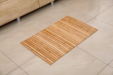 Photo of Wooden mat on floor in bathroom. Interior design