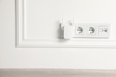 Photo of Wireless Wi-Fi repeater on white wall indoors, space for text