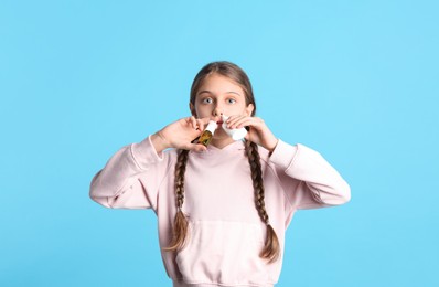 Photo of Sick little girl using nasal sprays on light blue background
