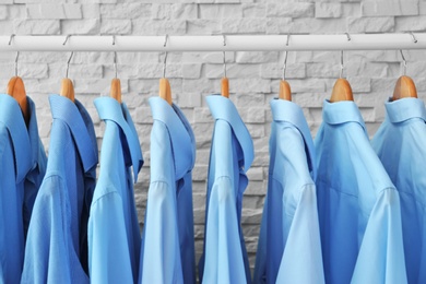 Rack with clean clothes on hangers after dry-cleaning indoors