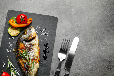 Delicious roasted fish and vegetables on grey table, flat lay