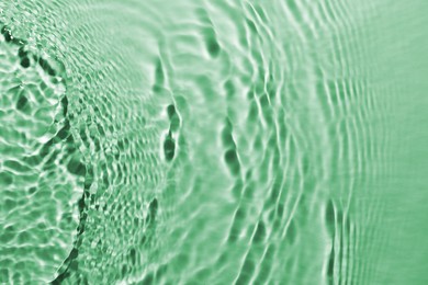 Rippled surface of clear water on green background, top view