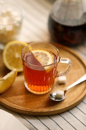 Photo of Glass mug of aromatic tea with lemon on table, closeup