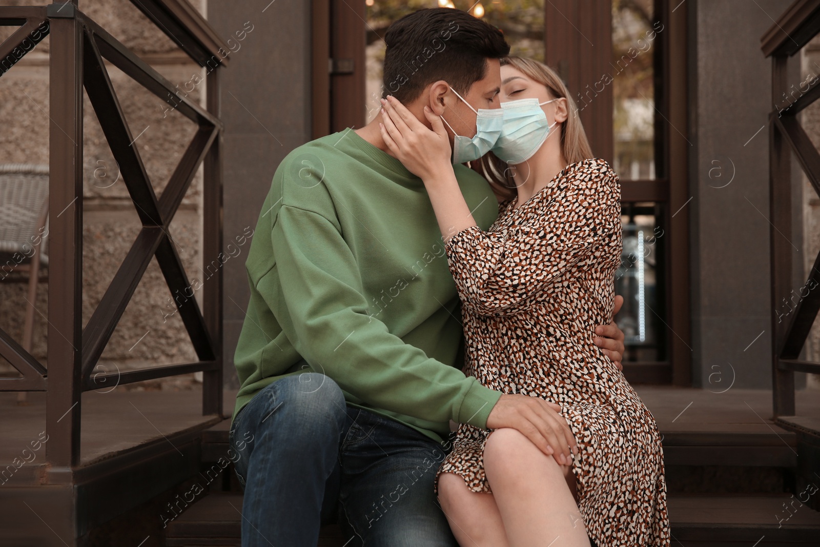 Photo of Couple in medical masks trying to kiss outdoors