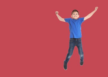 Image of Happy boy jumping on red background, space for text