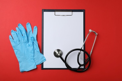 Clipboard with space for text, stethoscope and rubber gloves on color background, top view. Medical objects