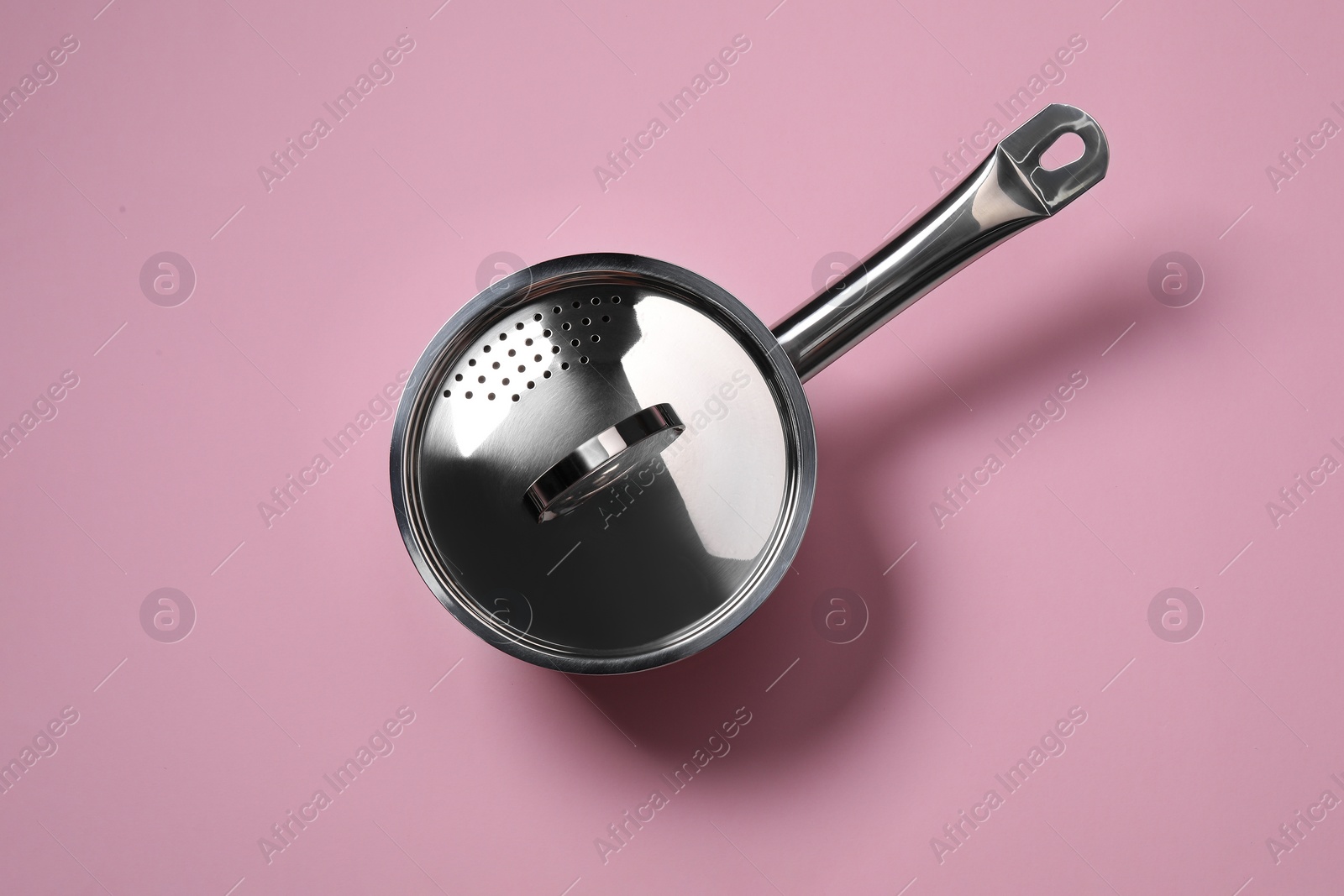 Photo of Steel saucepan with lid on pink background, top view
