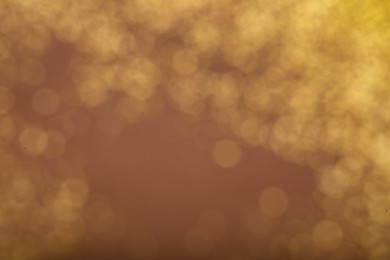 Photo of Blurred view of golden lights on dusty rose background. Bokeh effect