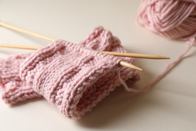 Photo of Pink knitting and needles on beige background, closeup