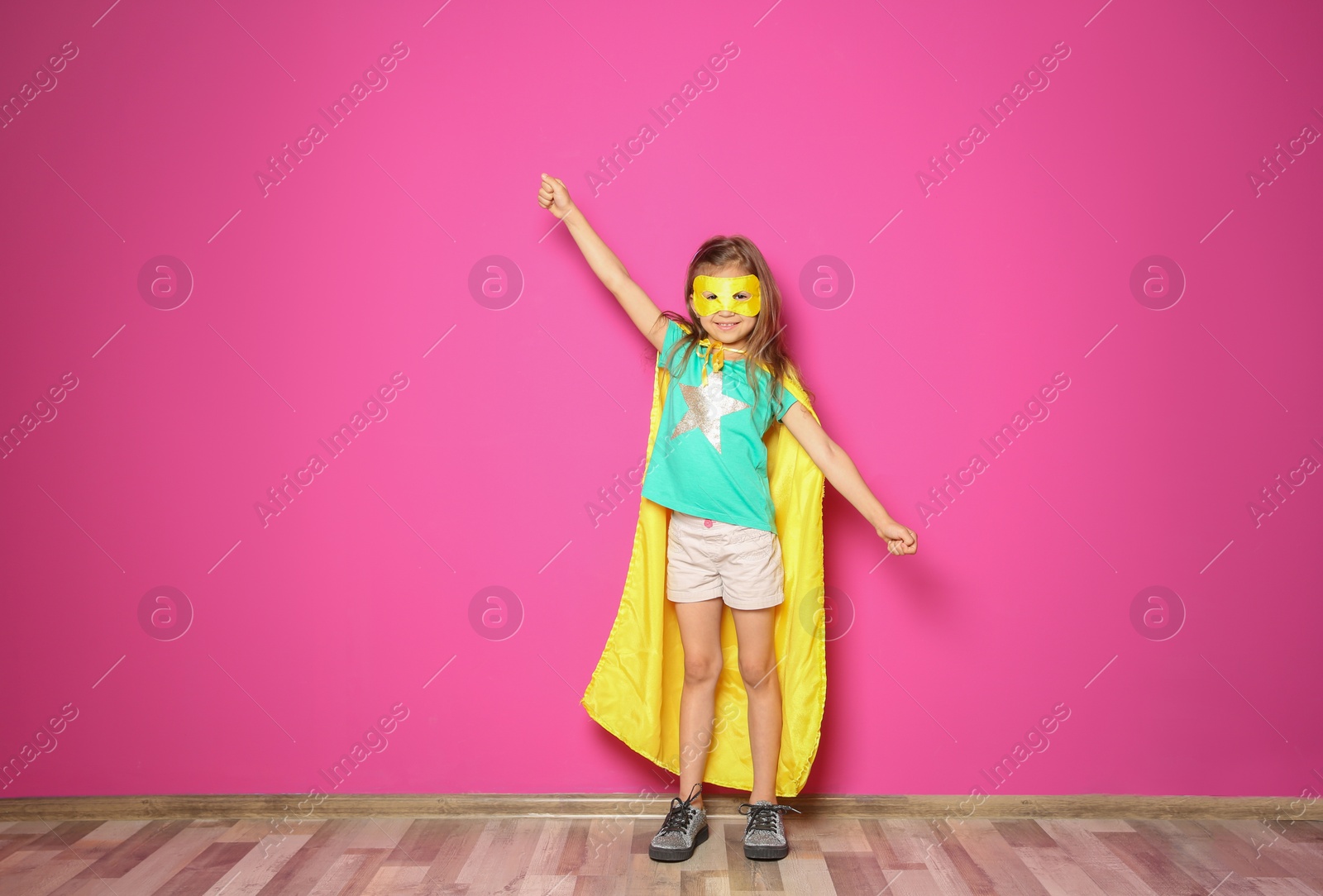 Photo of Adorable little child playing superhero indoors