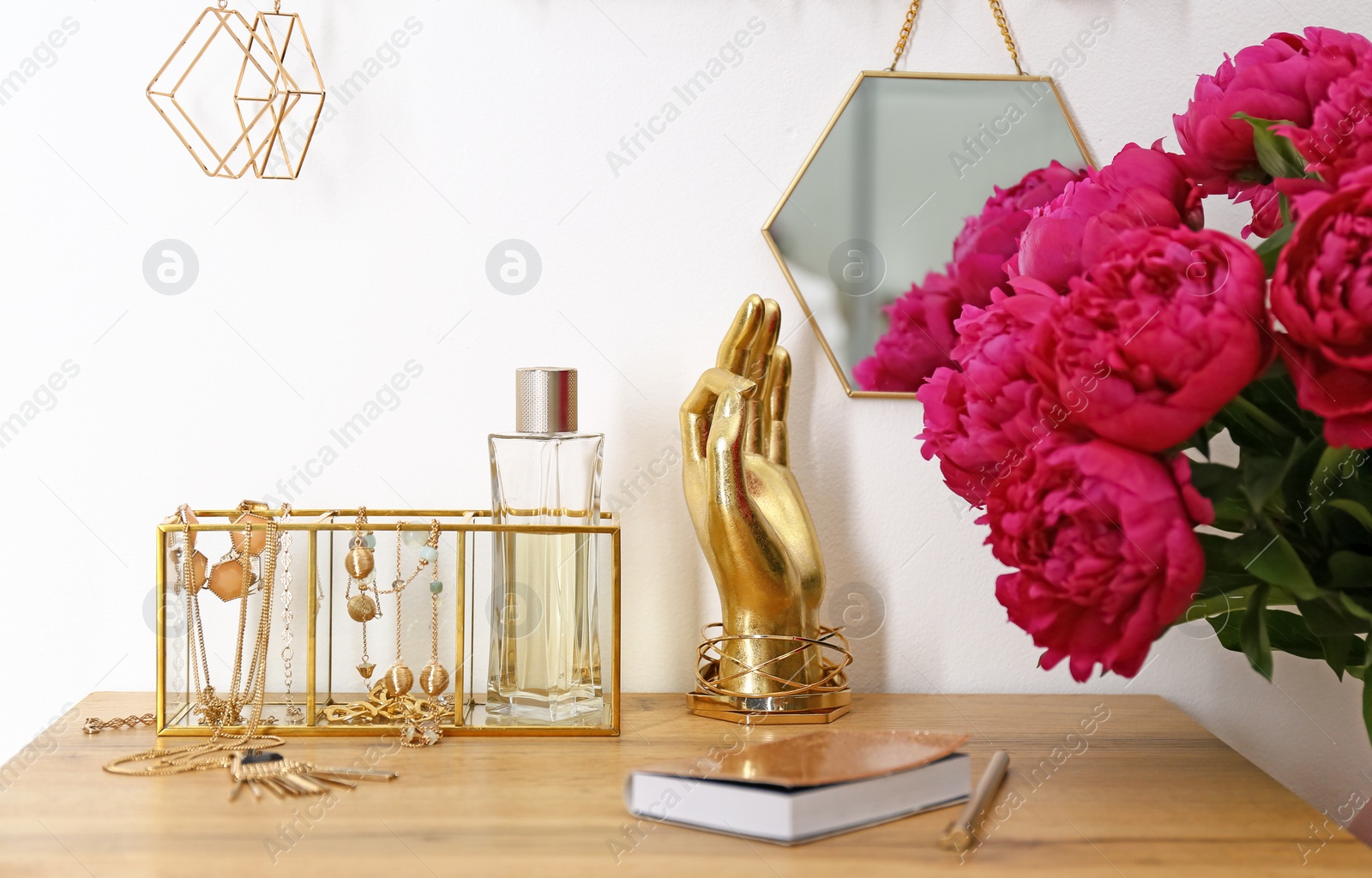 Photo of Composition with gold accessories and flowers on dressing table near white wall