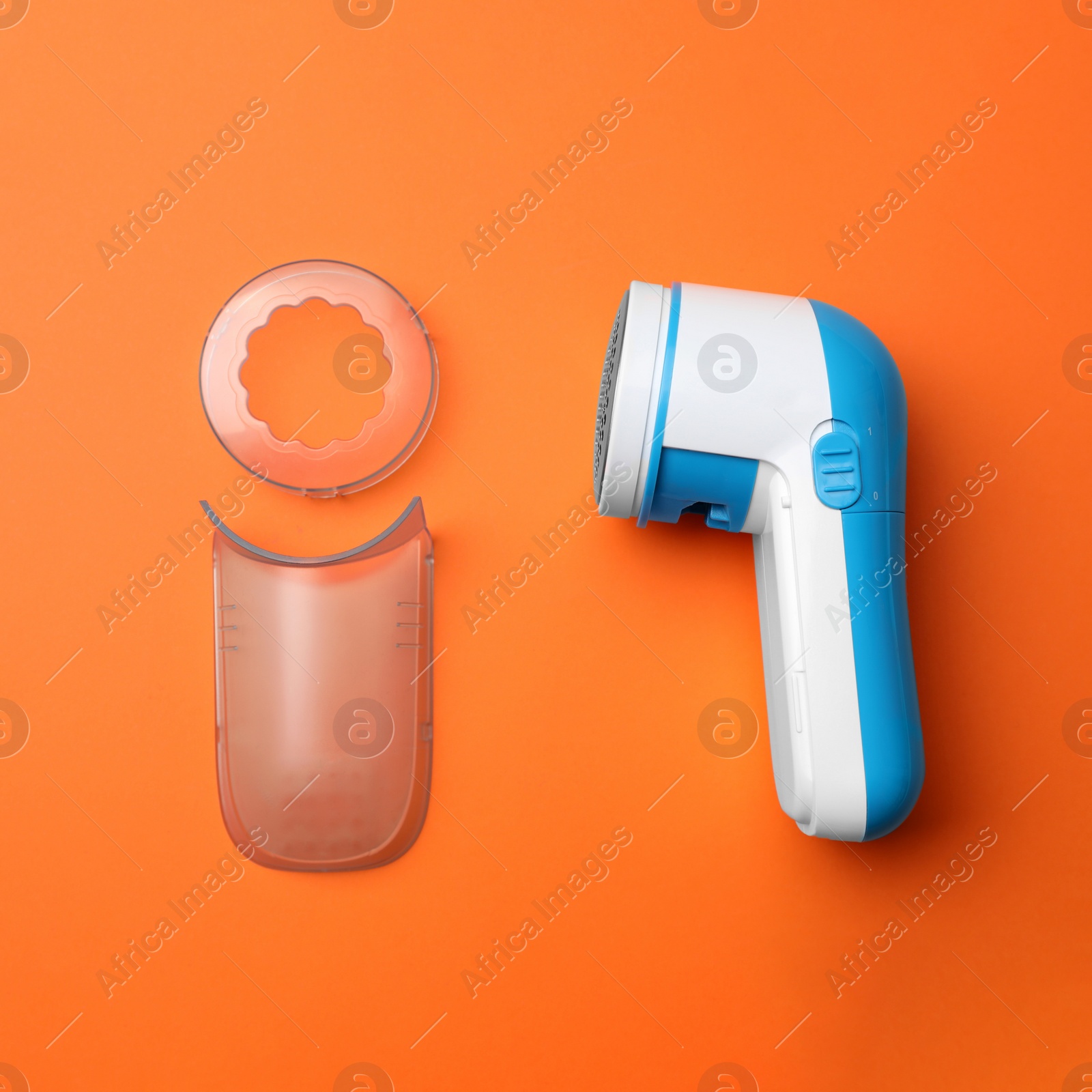 Photo of Modern fabric shaver and parts on orange background, flat lay