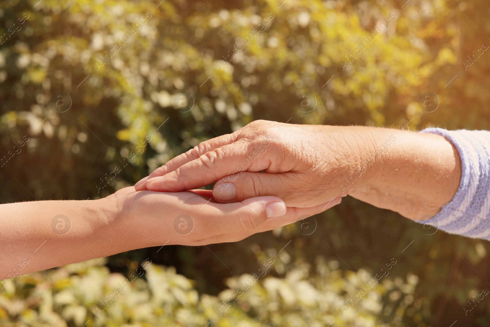 Photo of Helping hands on blurred background, closeup. Elderly care concept