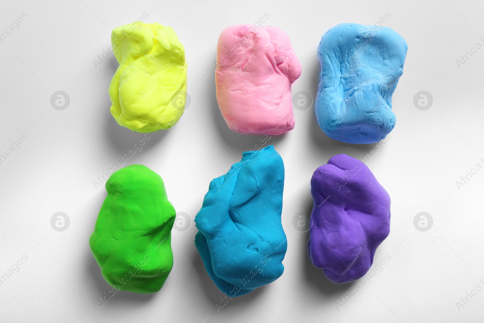 Photo of Different color play dough on white background, top view