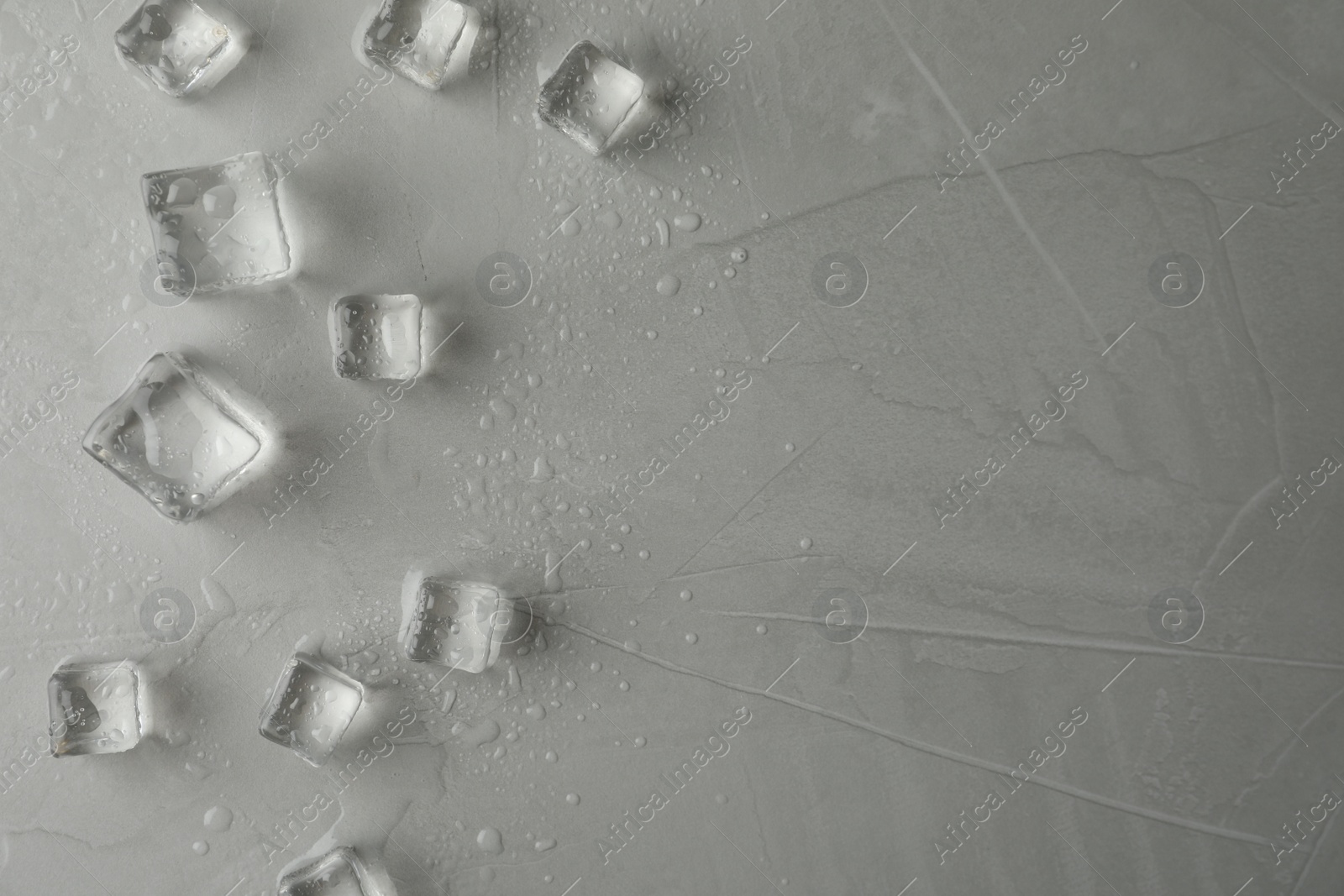 Photo of Crystal clear ice cubes with water drops on grey table, flat lay. Space for text