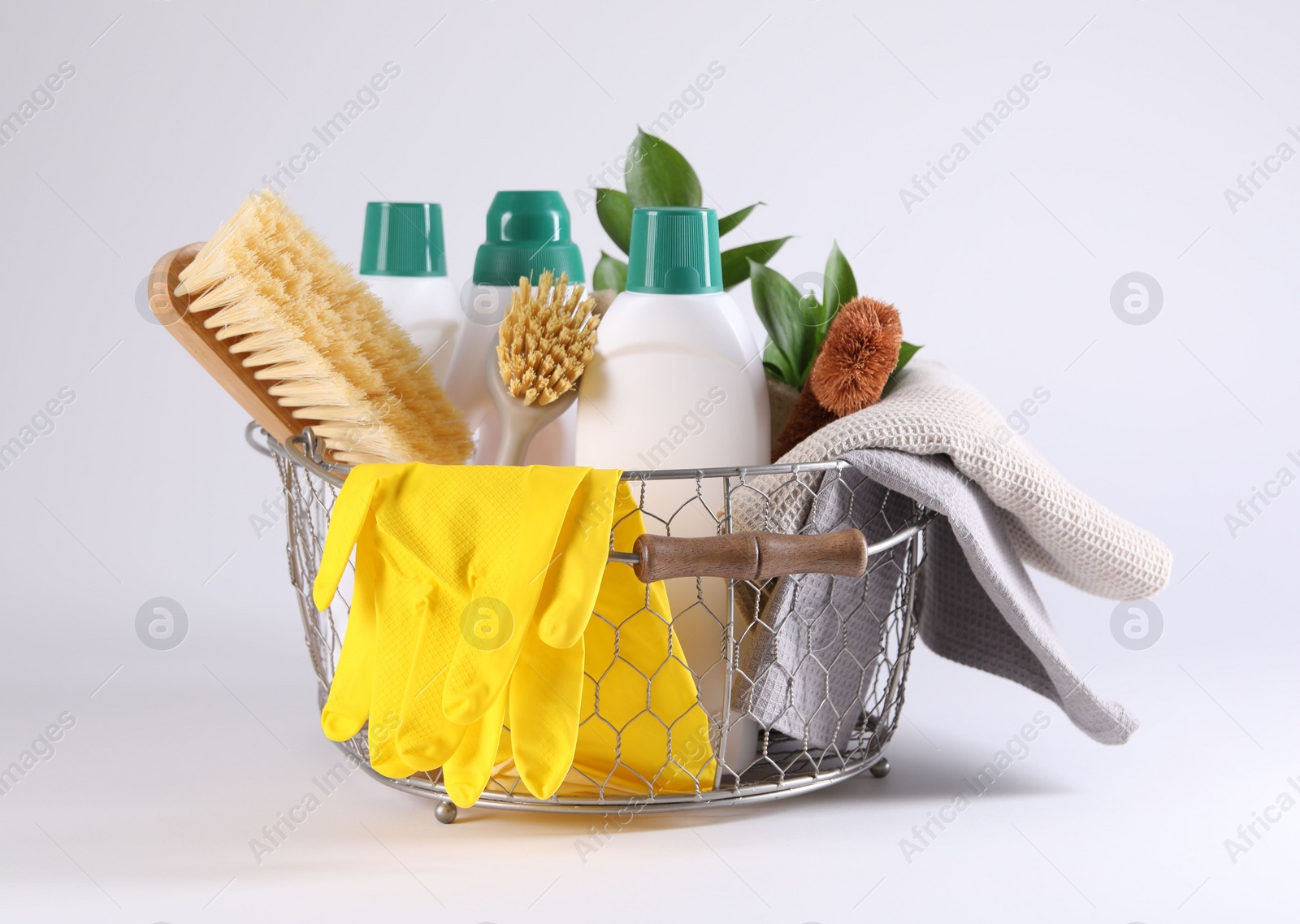 Photo of Set of different cleaning supplies in basket on white background