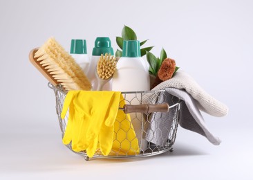 Photo of Set of different cleaning supplies in basket on white background