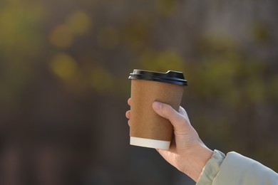 Photo of Woman with takeaway coffee cup outdoors, closeup