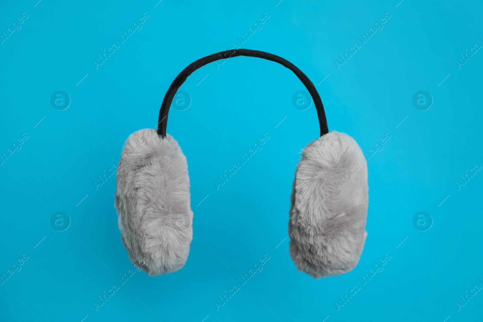 Photo of Stylish winter earmuffs on light blue background