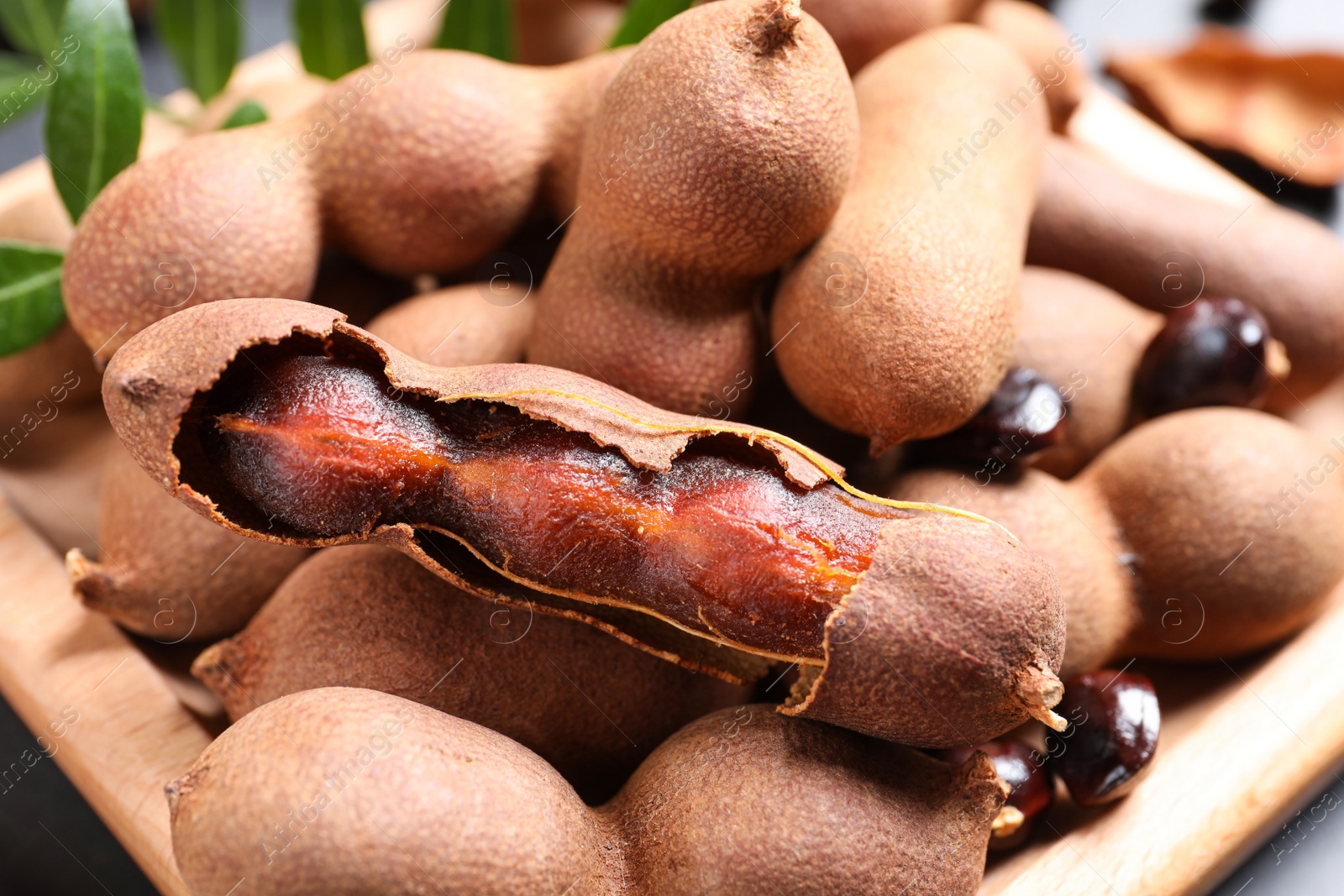 Photo of Delicious ripe tamarinds on wooden plate, closeup