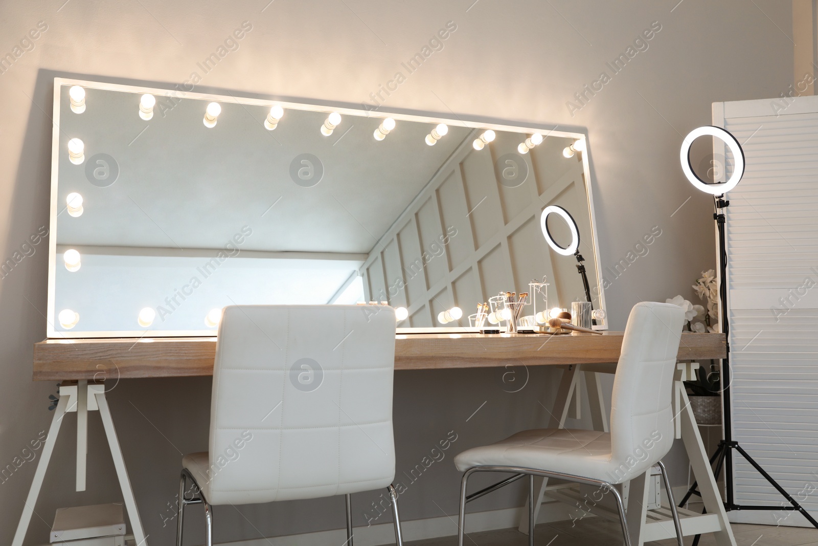 Photo of Modern mirror with light bulbs on dressing table in makeup room