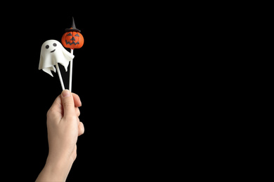 Woman with delicious cake pops and space for text on black background, closeup. Halloween celebration