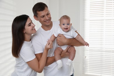 Photo of Happy family. Couple with their cute baby near window indoors