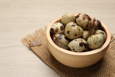 Photo of Speckled quail eggs on white wooden table, closeup. Space for text