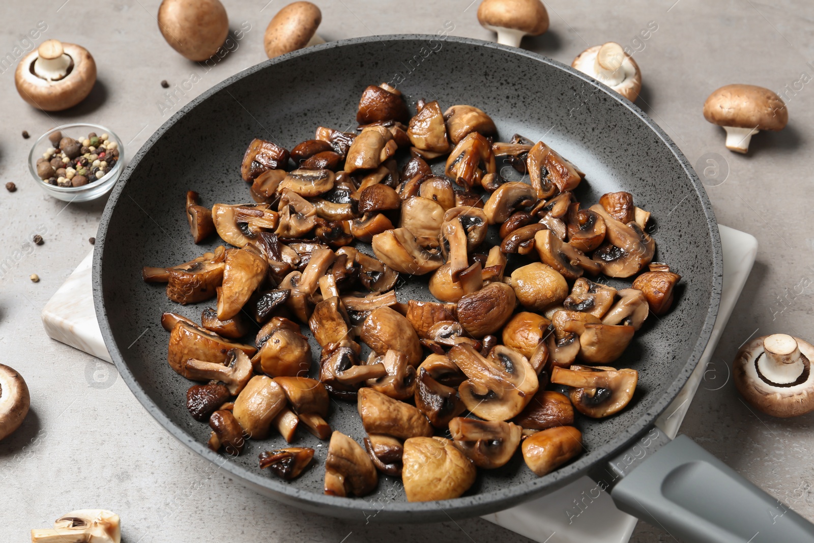 Photo of Frying pan with mushrooms on grey table