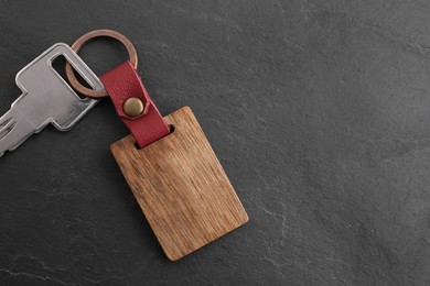 Photo of Key and wooden keychain with Ukrainian coat of arms on grey background, top view. Space for text