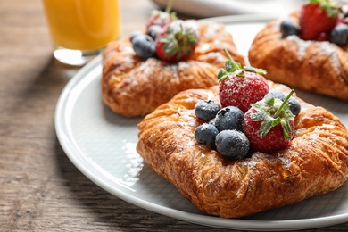 Photo of Fresh delicious puff pastry with sweet berries on wooden table, closeup