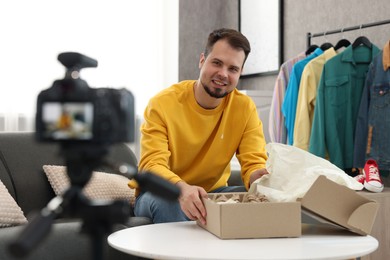 Photo of Smiling fashion blogger with parcel recording video at home