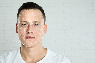 Image of Facial recognition system. Young man with biometric identification scanning grid near brick wall, space for text