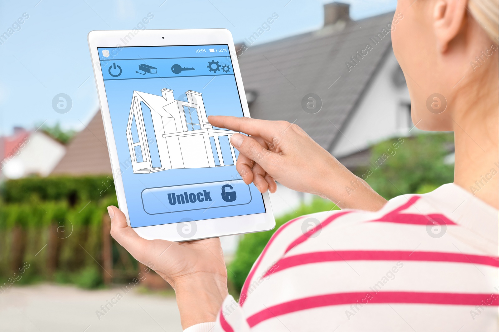 Image of Woman using home security system application on tablet outdoors, closeup