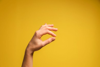 Photo of Woman holding something in hand on yellow background, closeup. Space for text