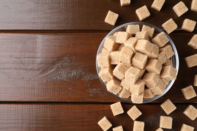 Photo of Brown sugar cubes on wooden table, flat lay. Space for text