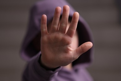 Photo of Child abuse. Boy with doing stop gesture on light background, selective focus