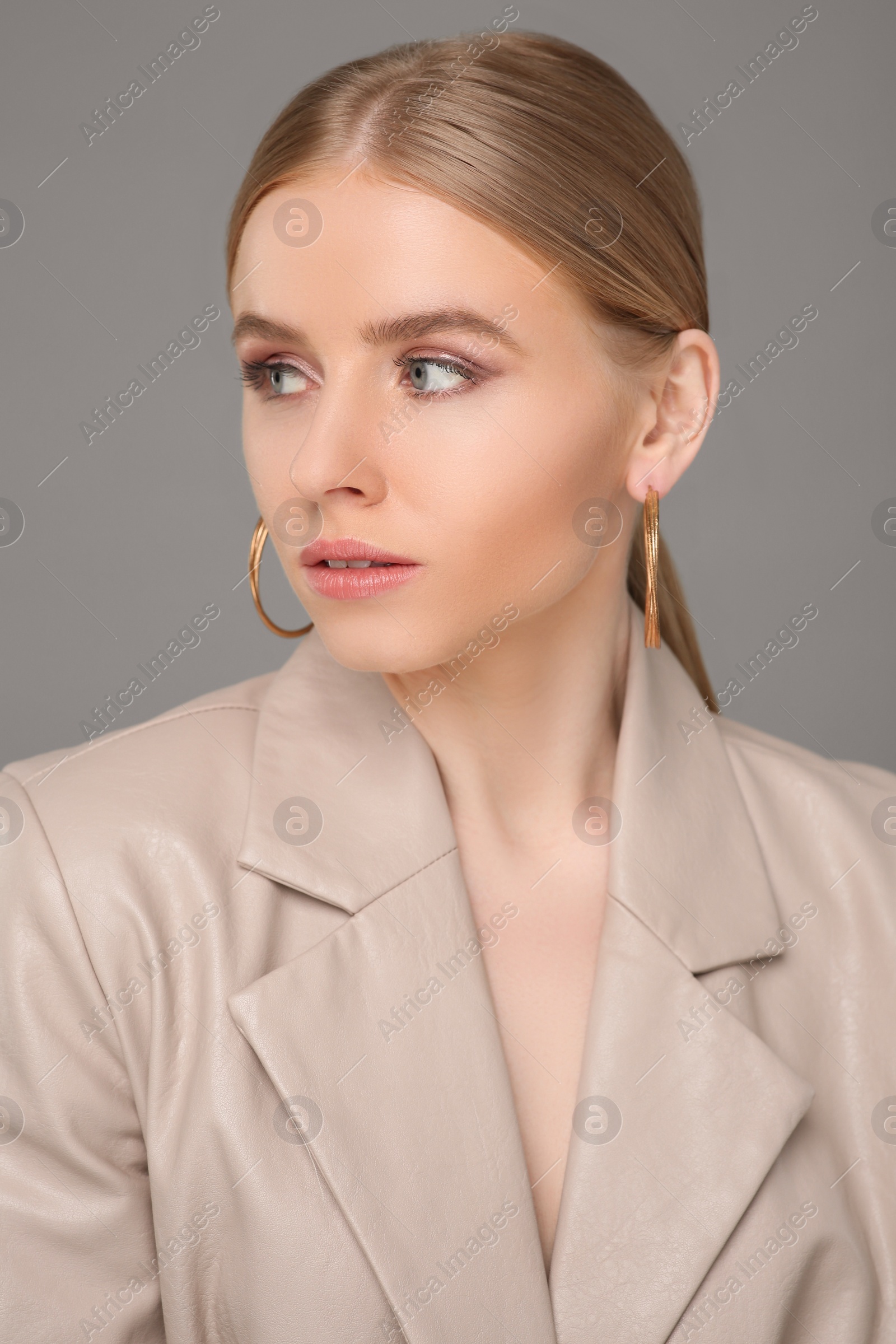 Photo of Beautiful young woman with elegant earrings on gray background