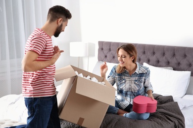 Photo of Young couple opening parcel in bedroom at home