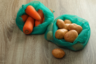 Net bags with vegetables on wooden table