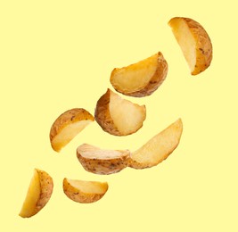 Image of Tasty baked potatoes falling on beige background