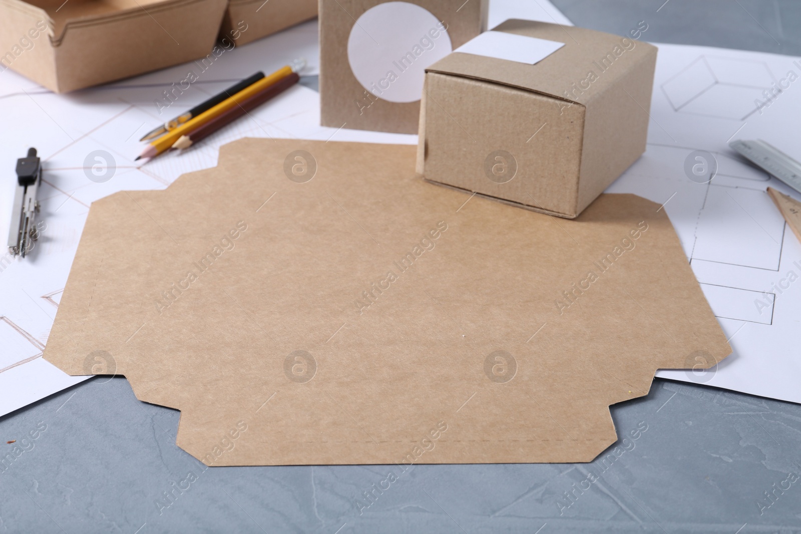 Photo of Creating packaging design. Drawings, boxes and stationery on blue textured table, closeup