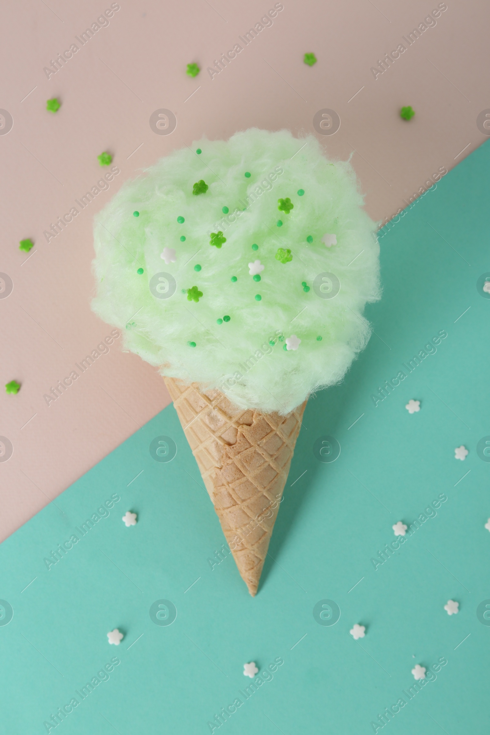 Photo of Sweet cotton candy in waffle cone on color background, top view