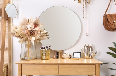 Photo of Modern wooden dressing table with decorative elements and makeup products in room