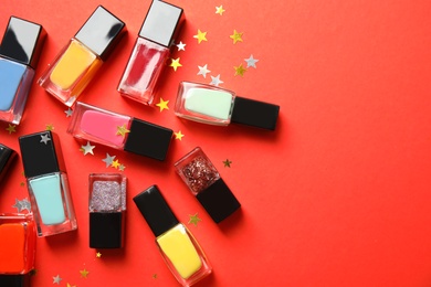 Bottles of nail polish on color background, top view with space for text