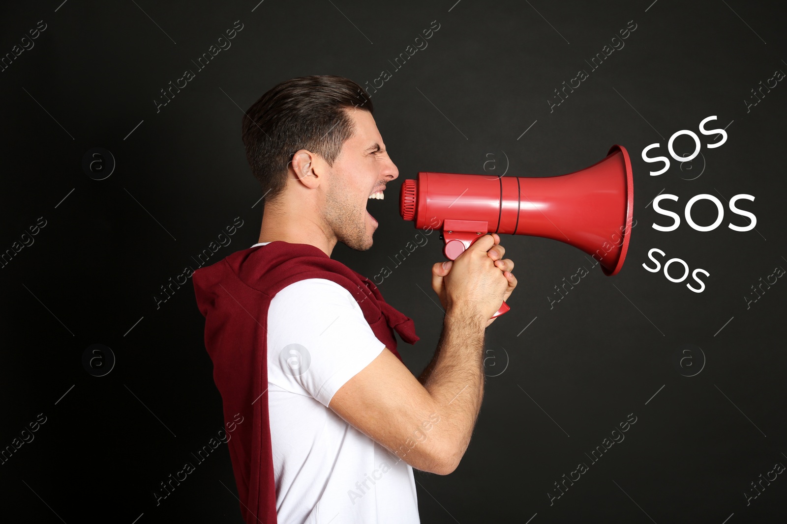 Image of Man with red megaphone and words SOS on black background. Asking for help