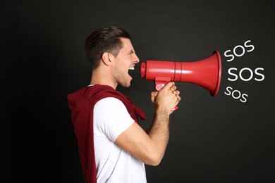 Man with red megaphone and words SOS on black background. Asking for help