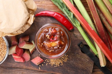 Photo of Tasty rhubarb sauce and ingredients on wooden table, flat lay